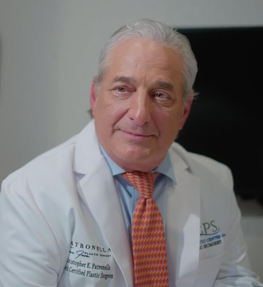 Portrait of Dr. Patronella wearing white lab coat, blue button up shirt, and an orange tie