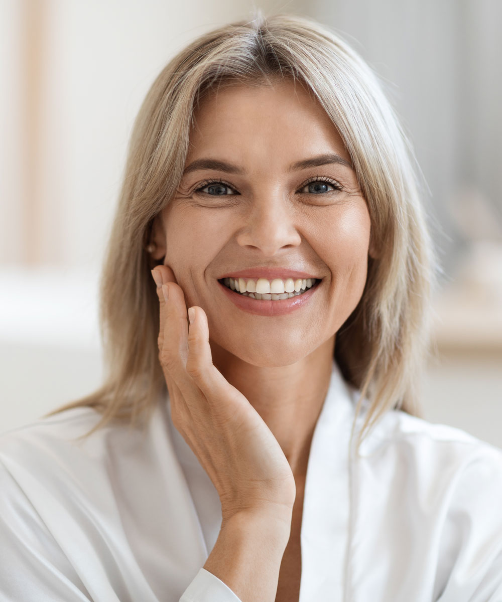 mature woman smiling and touching her face